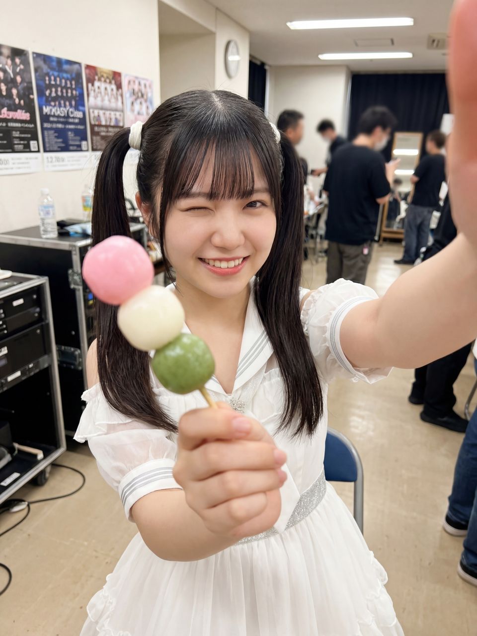 三色団子を持ってカメラを見つめ、茶目っ気たっぷりにウインクする葉月柚子