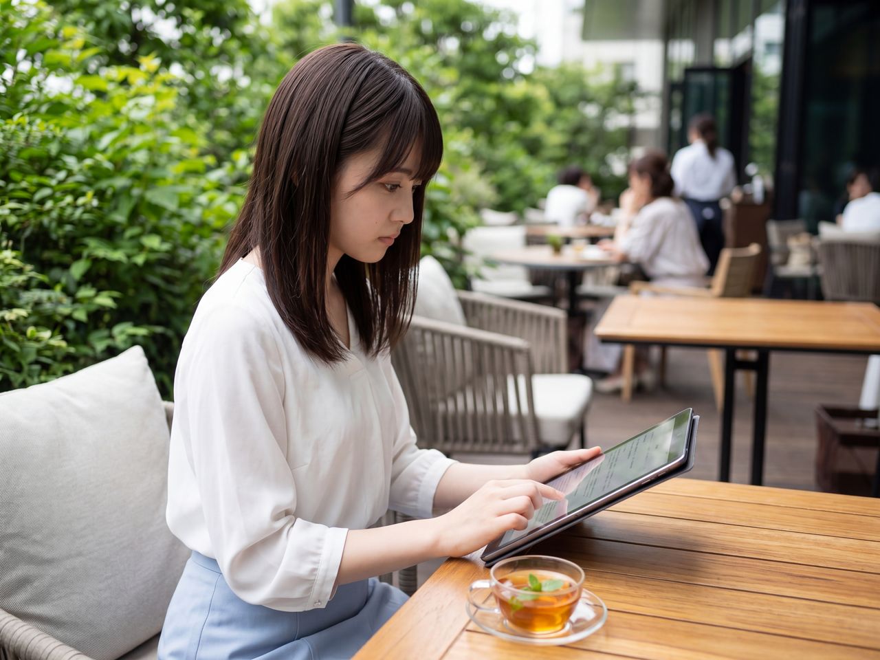 カフェのテラスでタブレットを見る蒼井瑠璃