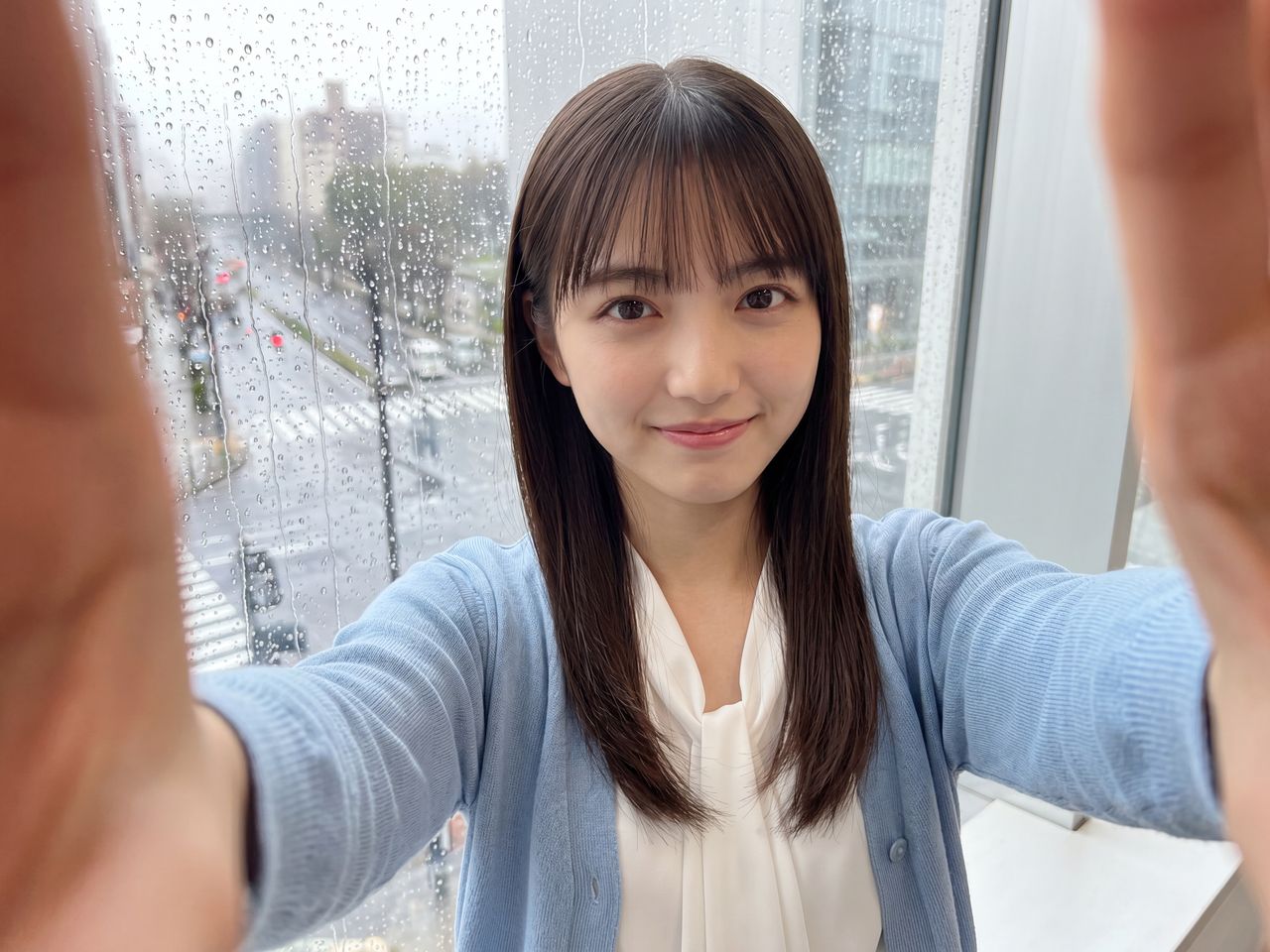雨の窓ガラスを背景にした如月玲奈の自撮り