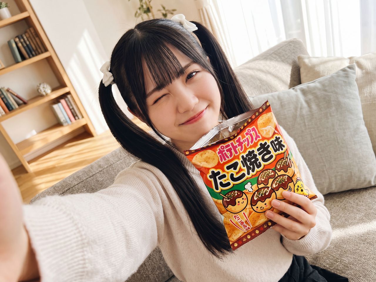 たこ焼き風スナックを片手にウインクする葉月柚子