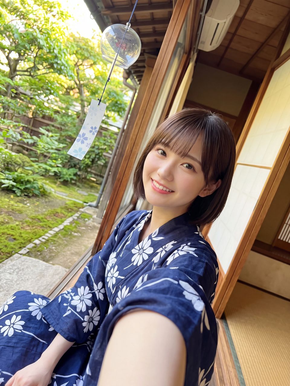 浴衣を着て風鈴を見つめ微笑む白石紬
