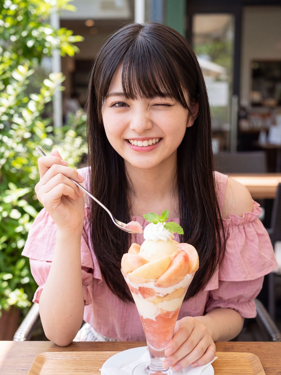 カフェのテラス席で豪華なピーチパフェを前にウインクする姫宮桃