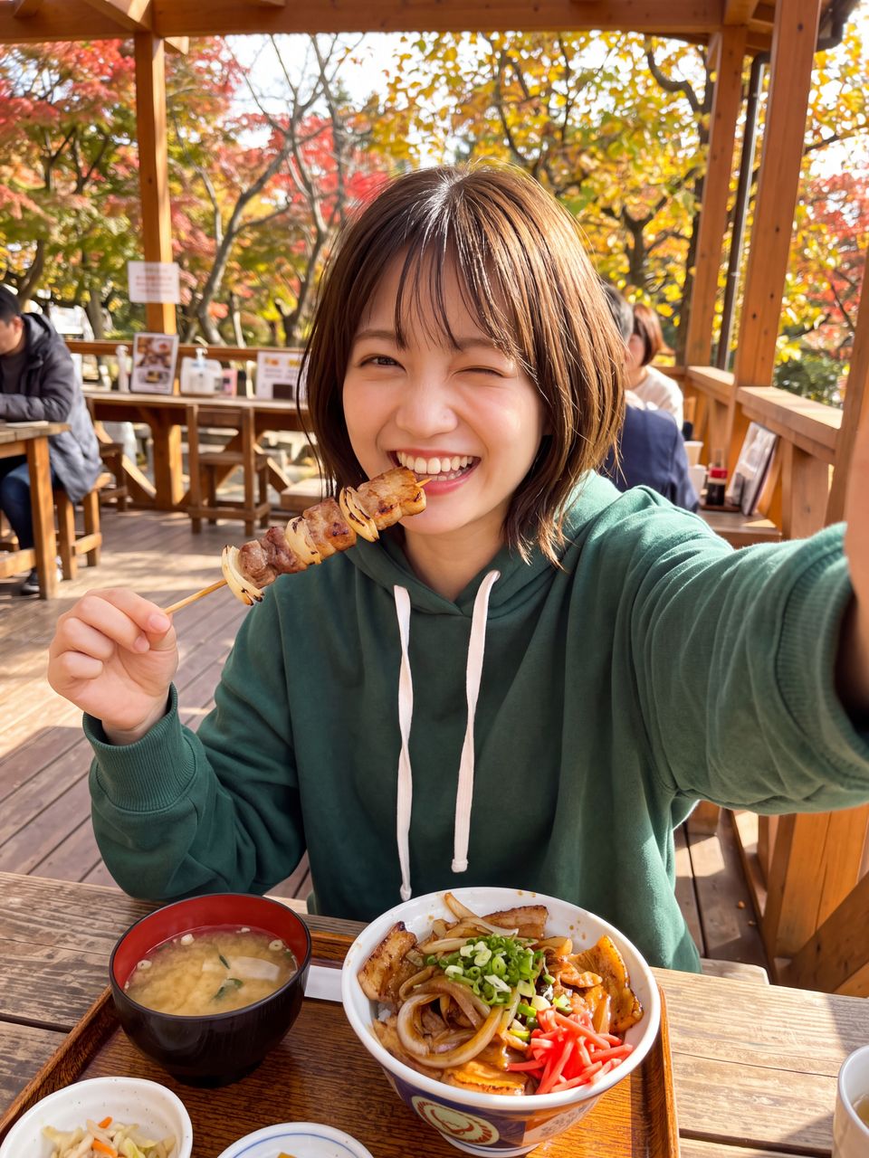 紅葉が見えるテラス席で香ばしい串焼きをくわえてウインクし、豚バラ丼を前に豪快な笑顔で自撮りする神楽坂舞