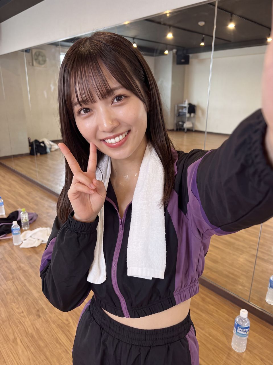 レッスン後のスタジオでタオルを首にかけ、満面の優しい笑顔でピースサインをして自撮りする橘ひかり